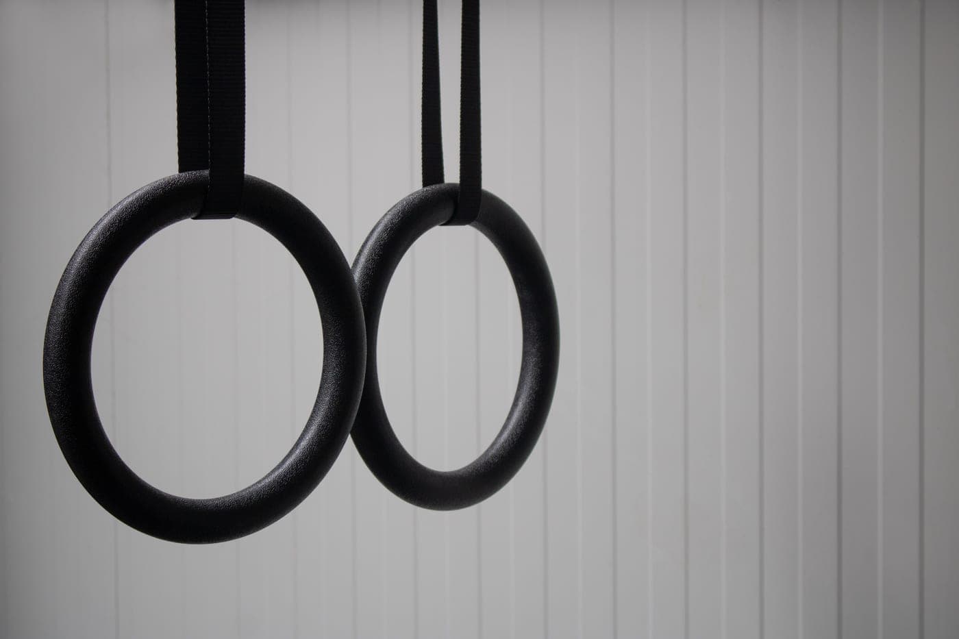 Wooden gymnastic rings hanging on straps in a home gym