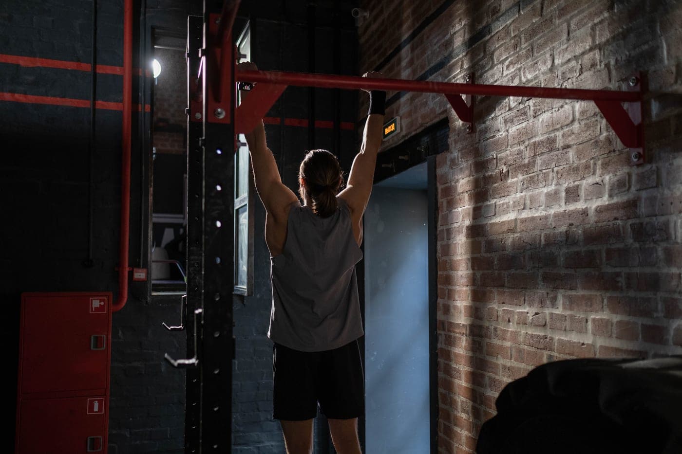 A man in activewear doing pull-ups on an indoor bar