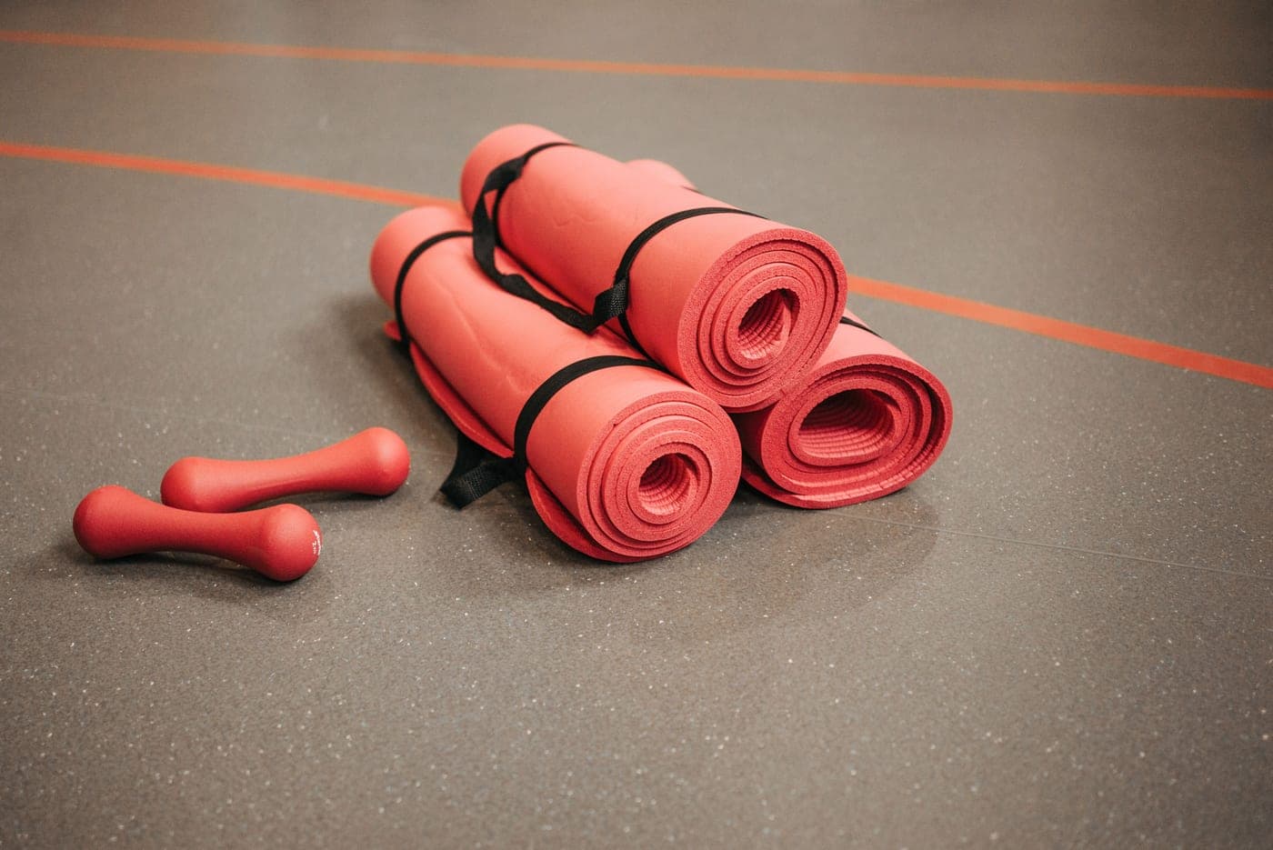 Rolled exercise mats and dumbbells on a gym floor
