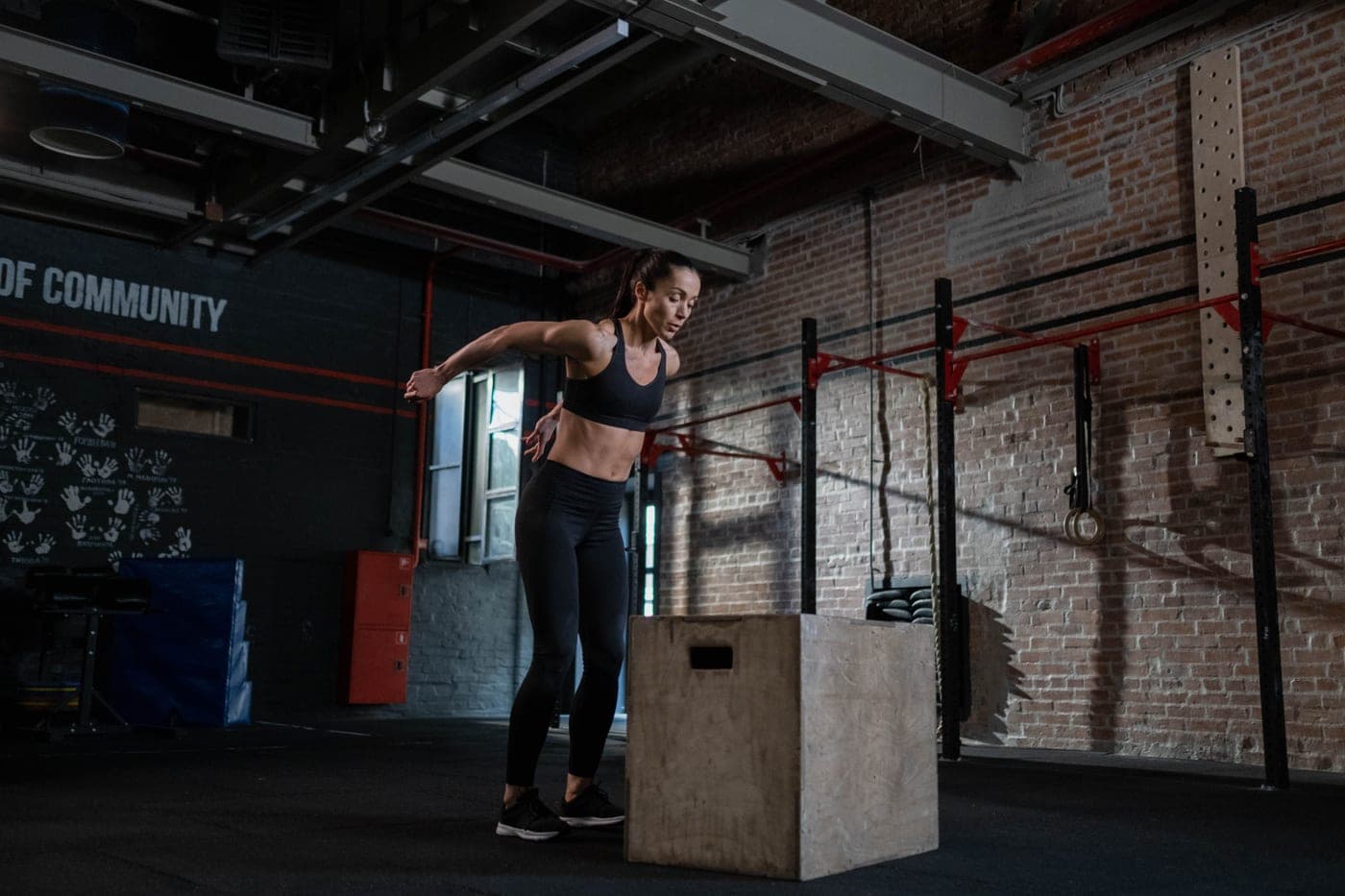 A woman performing a box jump in an industrial-style gym