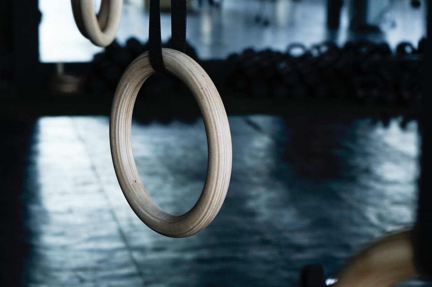 Wooden gymnastic rings hanging in a dimly lit gym