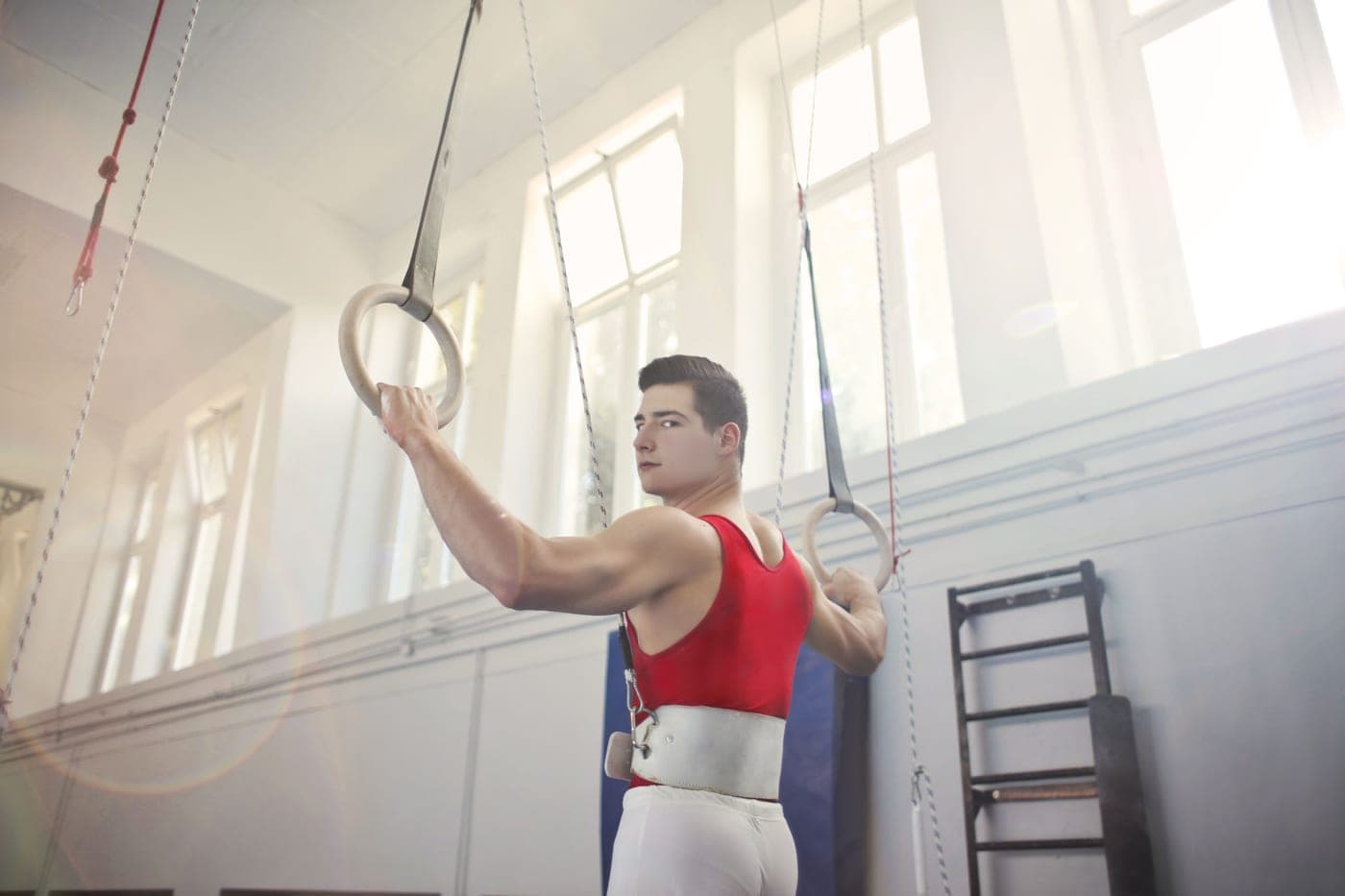 A man training on gymnastic rings indoors