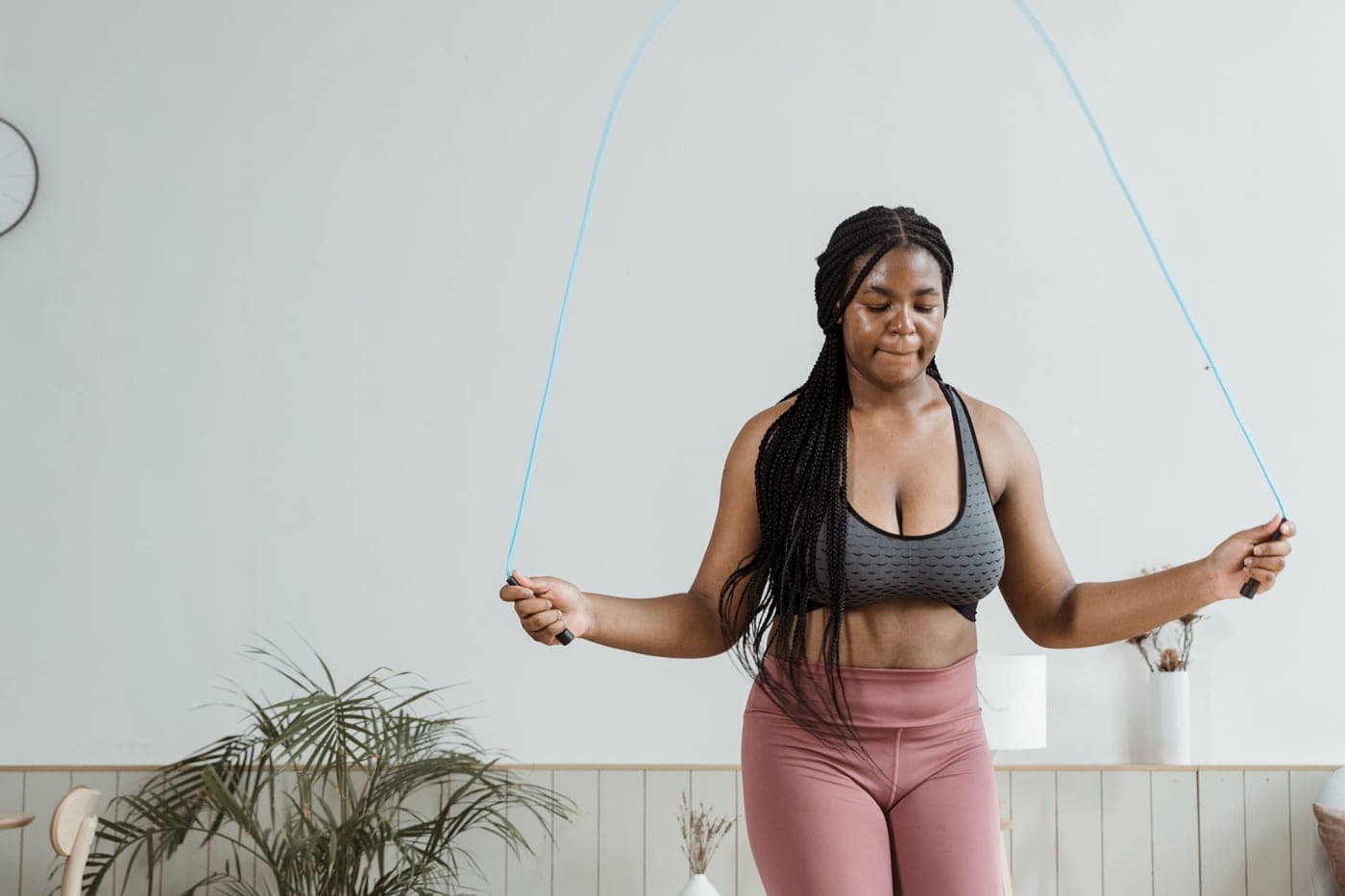 A woman in activewear jumping rope indoors