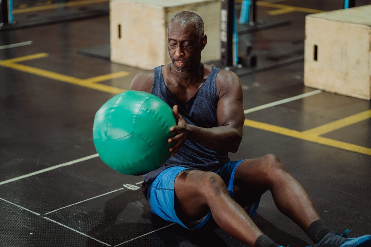 A man holding a weighted ball at chest height during a workout
