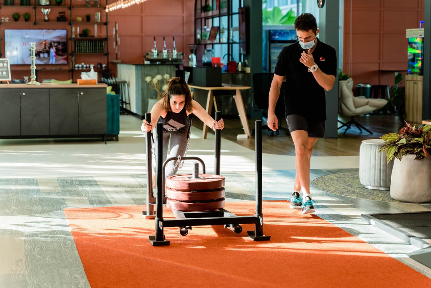 A woman pushing a weighted sled in a gym