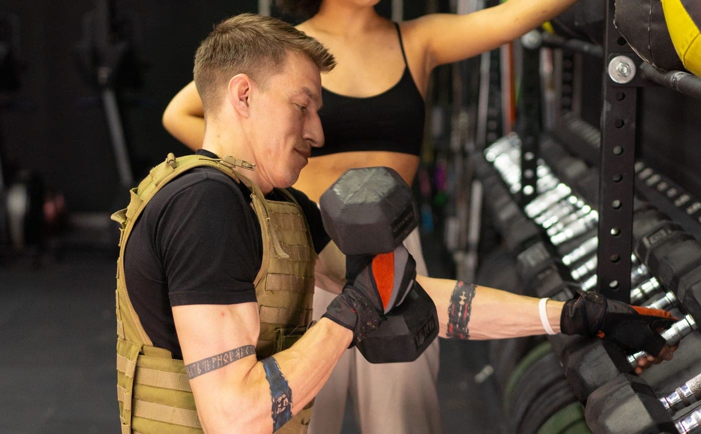 A man working out in a weighted vest in a gym