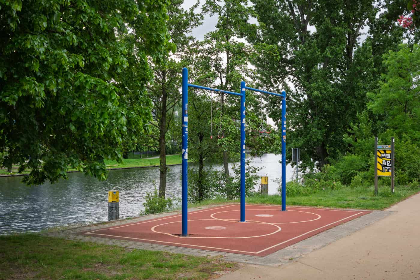 An outdoor calisthenics exercise area with steel bars beside a river